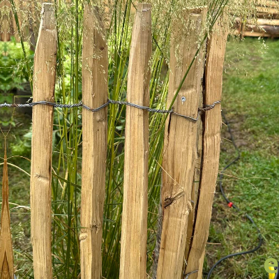Geplaatste kastanje schapenafsluiting in een bloeiende tuin voor een natuurlijke en duurzame omheining