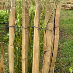 Geplaatste kastanje schapenafsluiting in een bloeiende tuin voor een natuurlijke en duurzame omheining